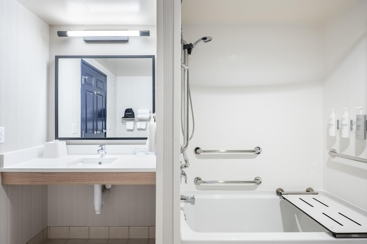 A modern bathroom with a sink, mirror, and shower.