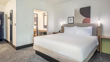 Una habitación de hotel con una cama grande, mesitas de noche, un espejo y una obra de arte colgada en la pared.