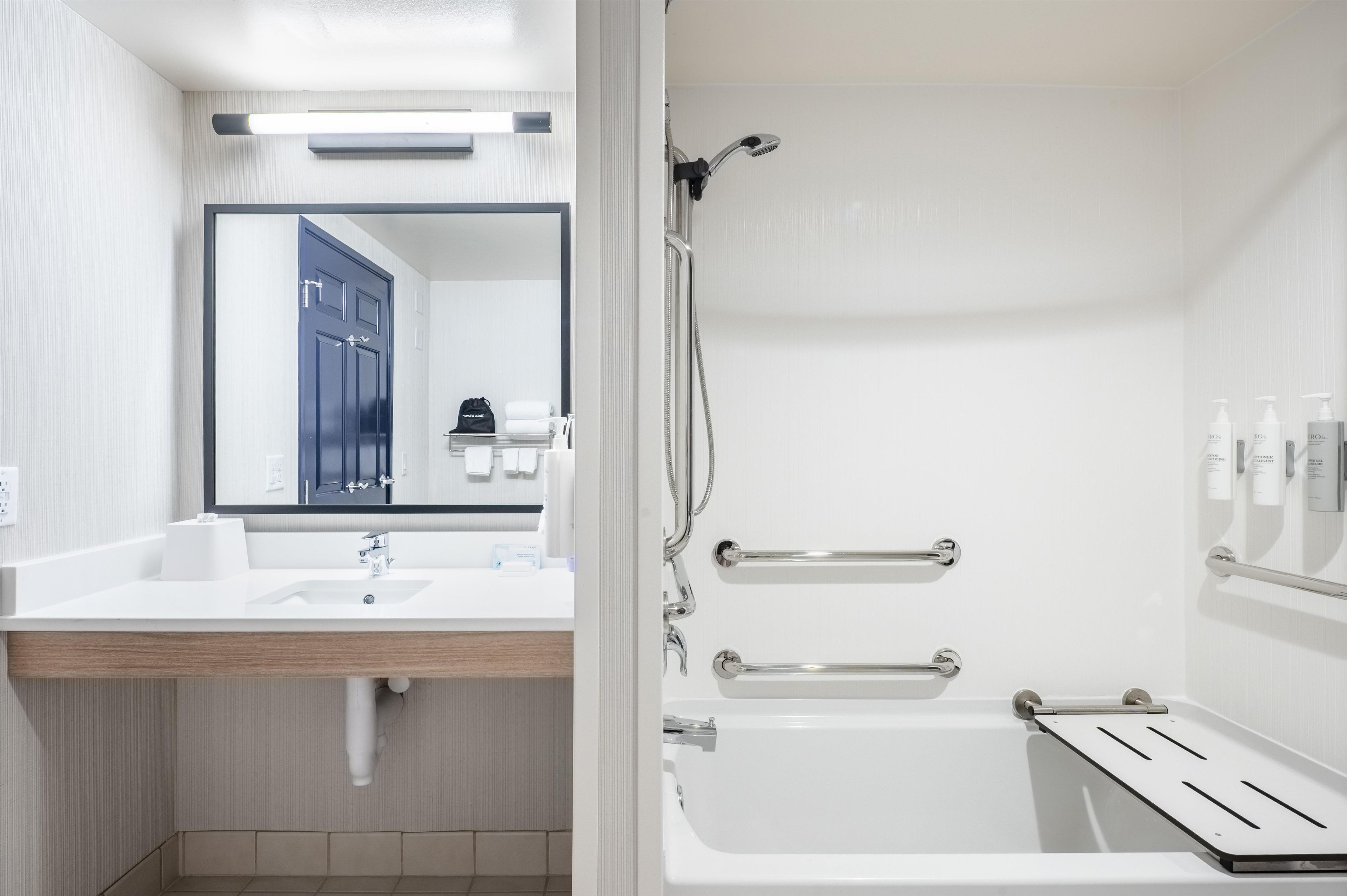 A modern bathroom with a white sink, mirror, and shower area.