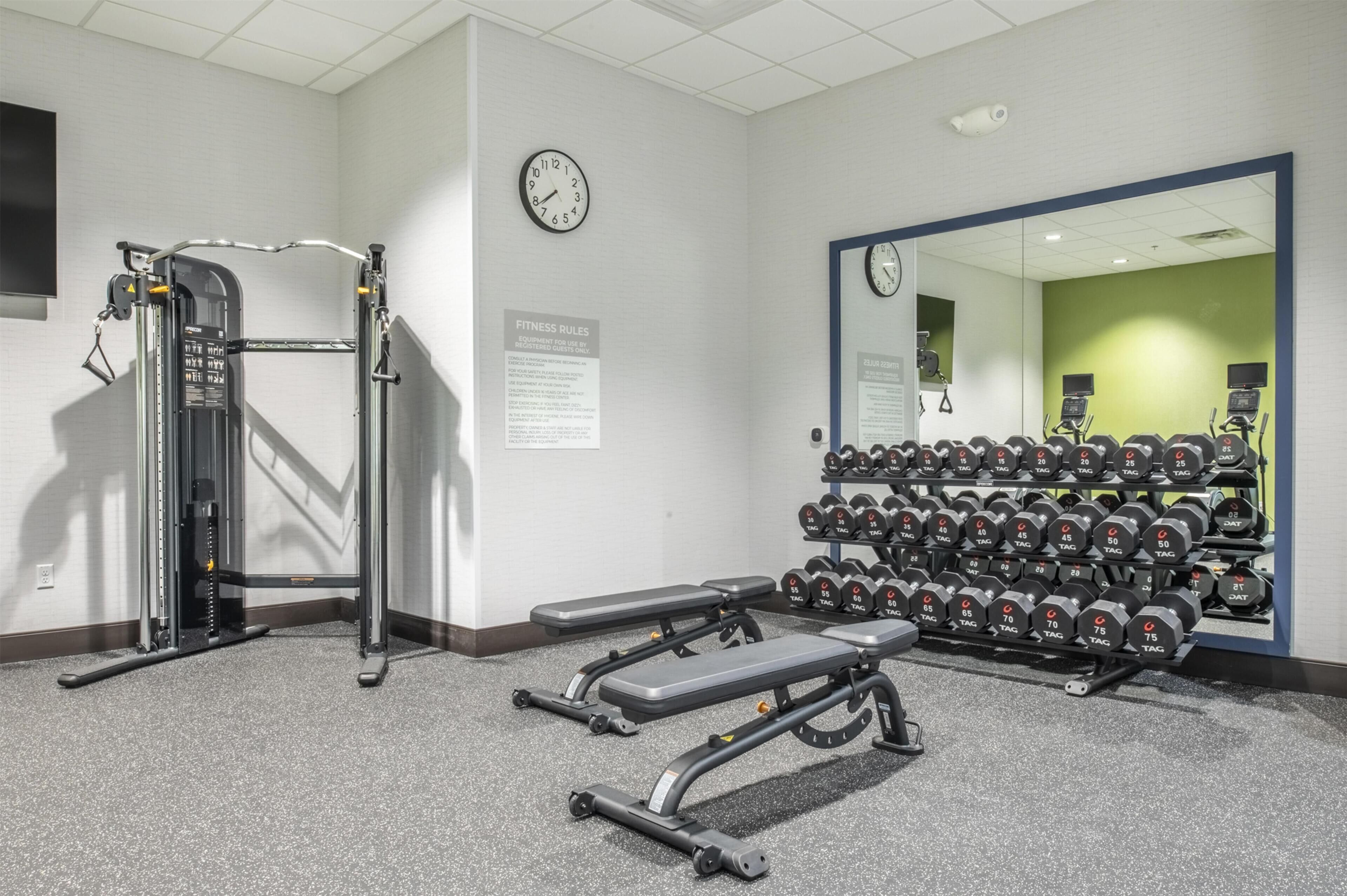 Une salle de sport équipée de matériel de musculation, d’haltères et de bancs.