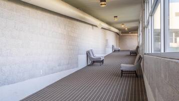 A corridor with a tiled floor, two chairs, and a wall with a ventilation duct.