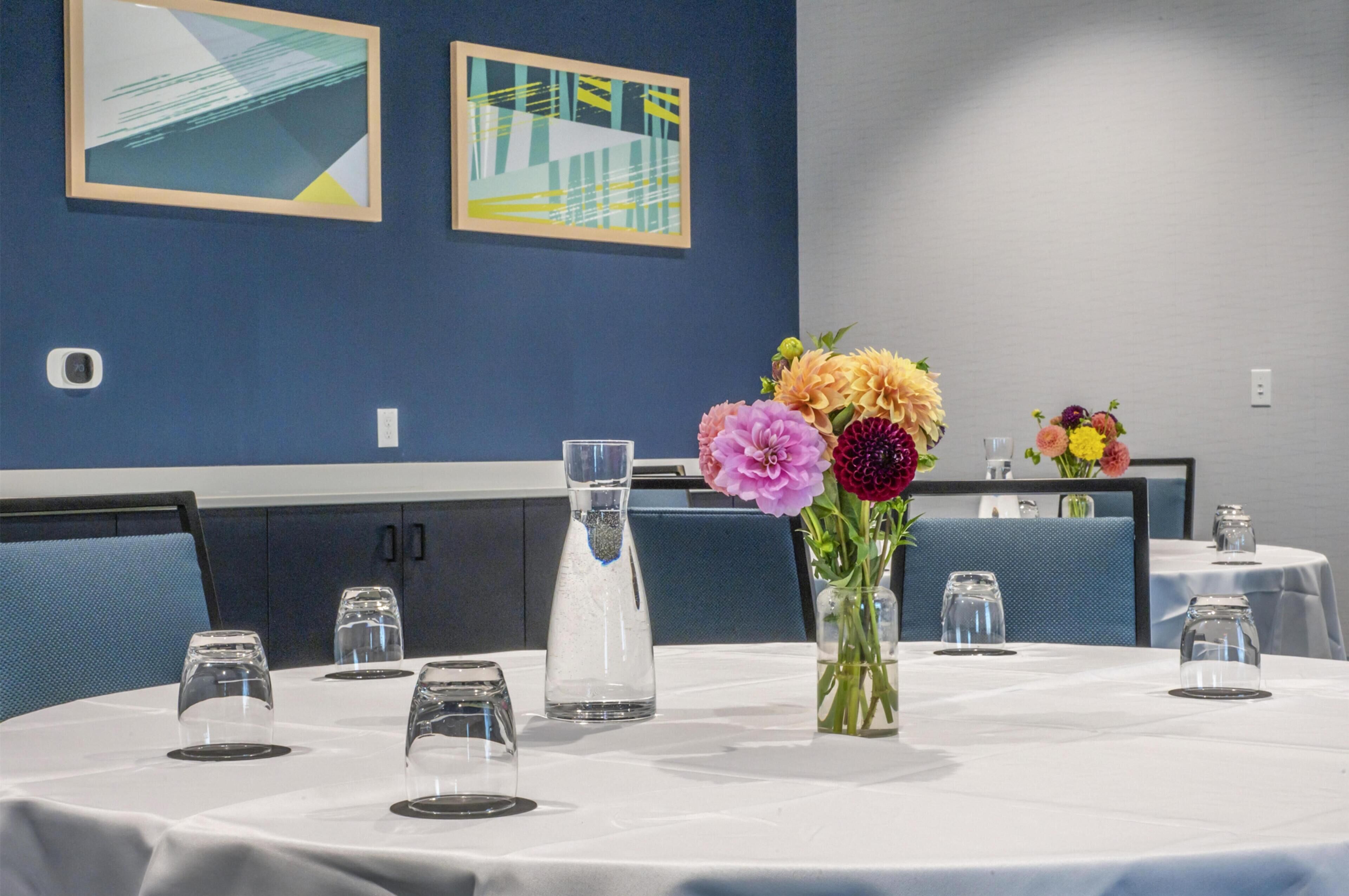 A dining area with round tables, chairs, and a vase of flowers.