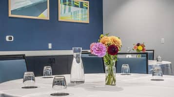A dining area with round tables, chairs, and a vase of flowers.