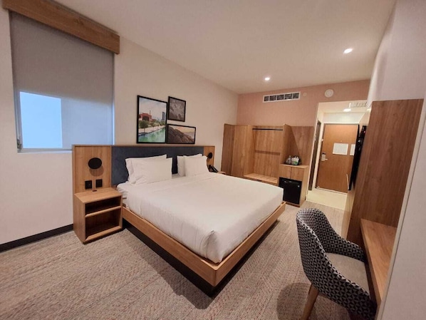 A modern hotel room with a large bed, a desk, and a chair.