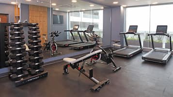 A gym with treadmills, dumbbells, and exercise equipment.