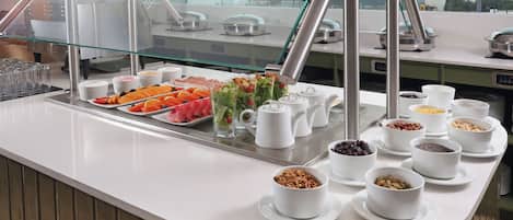 Zona de buffet con diversas opciones de comida y una vitrina de vidrio.