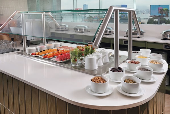Zona de buffet con diversas opciones de comida y una vitrina de vidrio.