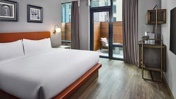 A hotel room with a large bed, a desk with a lamp, a window with curtains, and a view of the outside.
