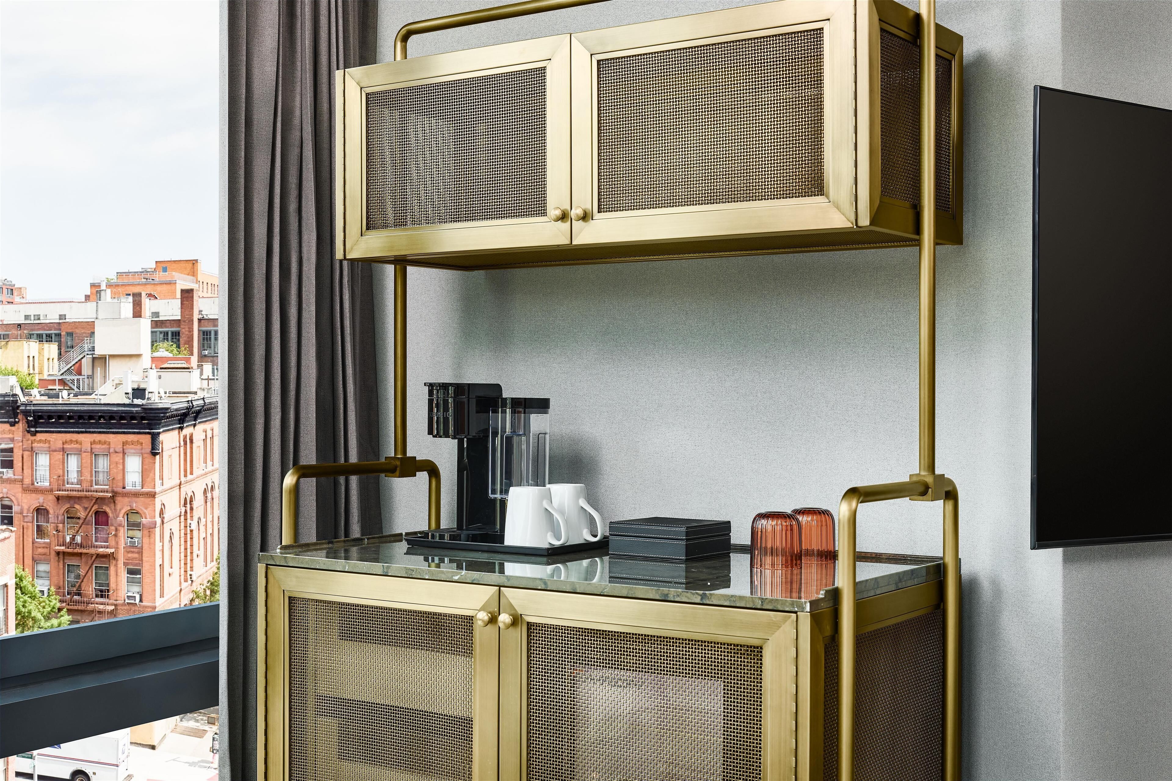 A modern room with a glass-top coffee table, a black coffee maker, and a flat-screen TV mounted on the wall.