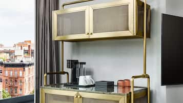 A modern room with a glass-top coffee table, a black coffee maker, and a flat-screen TV mounted on the wall.