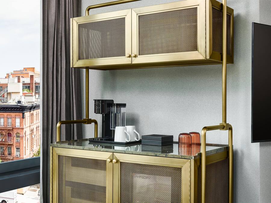 A modern room with a glass-top coffee table, a black coffee maker, and a flat-screen TV mounted on the wall.