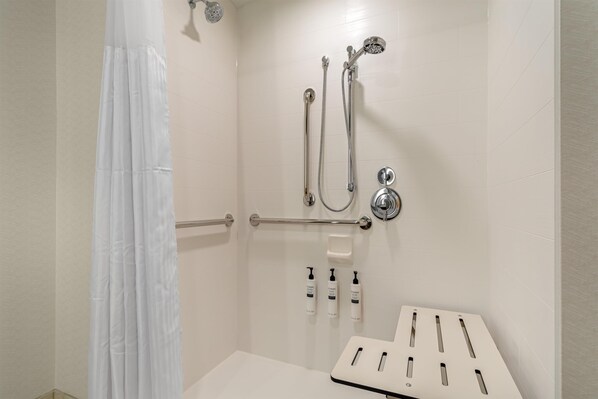 A shower with a handheld showerhead, a wall-mounted faucet, and a handheld showerhead. - Hilton Garden Inn Media Philadelphia (Media)