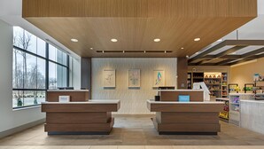 A hotel reception area with two reception desks, a large window, and a wall with framed artwork. - Hilton Garden Inn Media Philadelphia (Media)