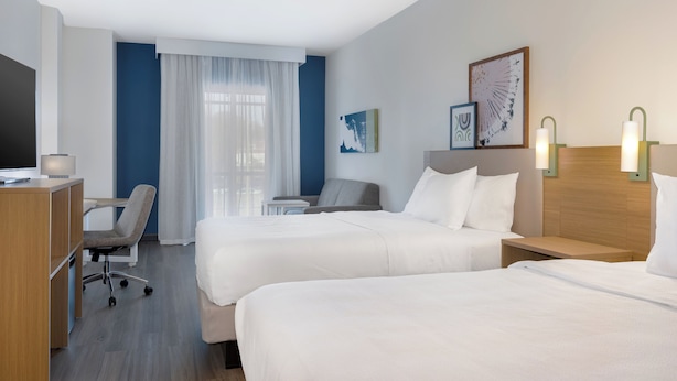 Een hotelkamer met twee bedden, een bureau, een stoel en een televisie.