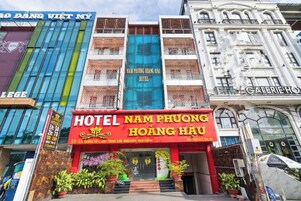 Um hotel chamado 'Hotel Nam Phuong Hoang Huu' com uma placa vermelha destacada, rodeado por outros edifícios.