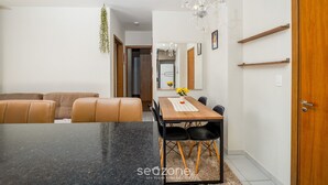 A dining area with a black granite table, brown leather chairs, a wooden dining table, and a chandelier. - Apt in Cond. c/ Pool 5min From the Beach Mar202 (Florianópolis)