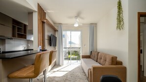 A modern kitchen with a bar area, a sofa, and a dining table. - Apt in Cond. c/ Pool 5min From the Beach Mar202 (Florianópolis)