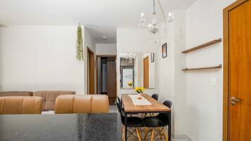 A dining area with a black granite table, brown leather chairs, a wooden dining table, and a chandelier.