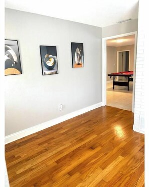 Un couloir doté d’un plancher en bois et orné de trois œuvres d’art encadrées au mur.