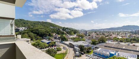 A cityscape with a view of a hill, buildings, and a parking lot.