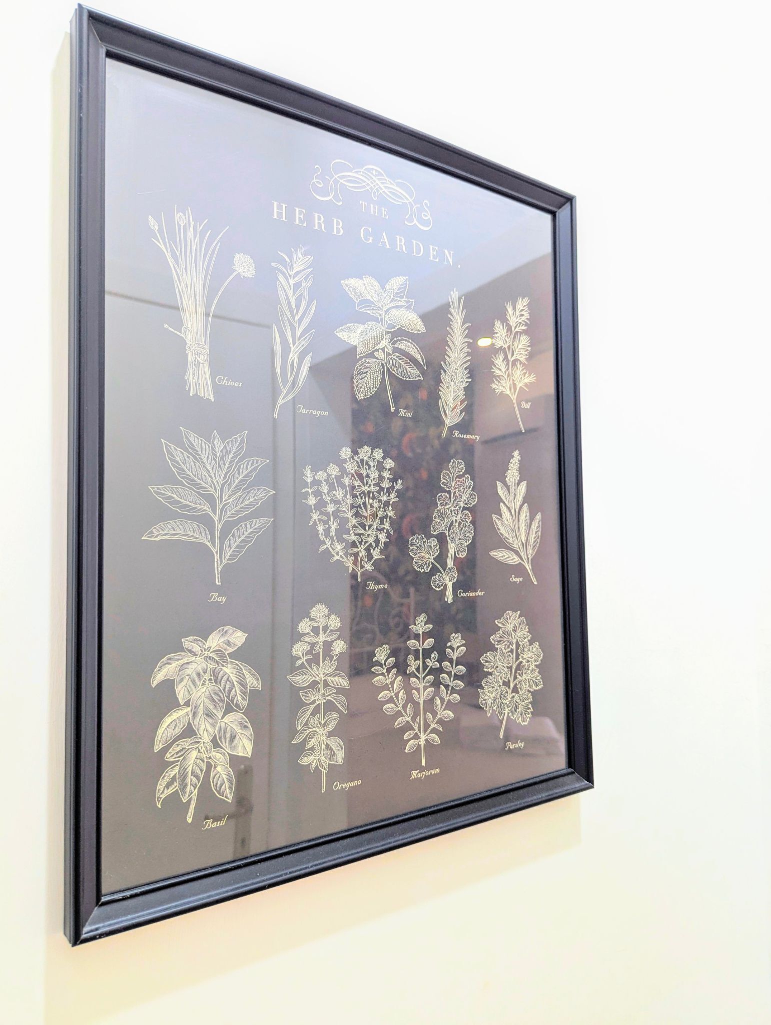 A framed botanical illustration titled "The Herb Garden" with various herb plants labeled.