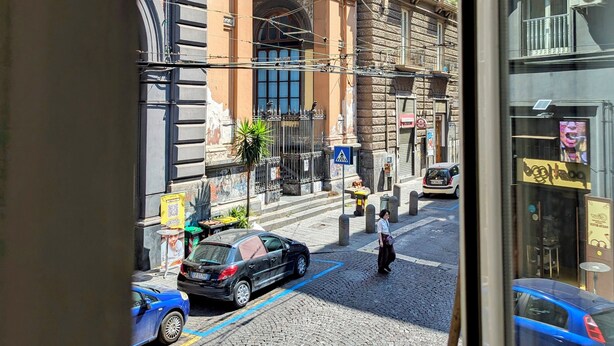 Straßenansicht mit historischen Gebäuden, Kopfsteinpflaster und parkenden Autos.