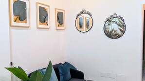 Ein modernes Wohnzimmer mit einem dunkelgrauen Ecksofa, einem Blumentopf und drei gerahmten Kunstwerken an der Wand.