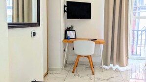 Ein modernes Zimmer mit Schreibtisch, Stuhl und einem an der Wand befestigten Fernseher.