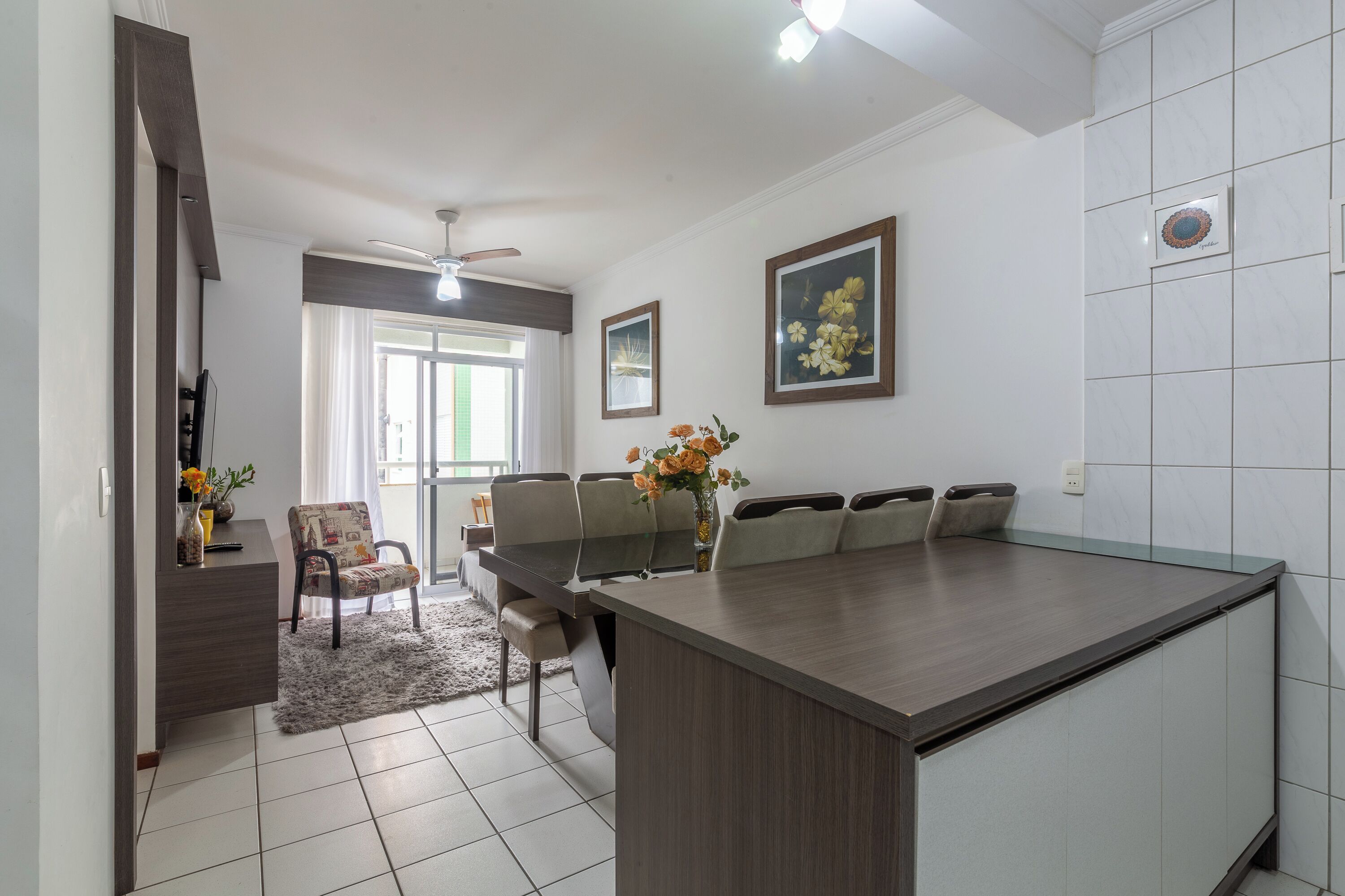 Een moderne keuken met een groot eiland, een eethoek met stoelen, en uitzicht op de woonkamer.