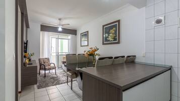 Een moderne keuken met een groot eiland, een eethoek met stoelen, en uitzicht op de woonkamer.