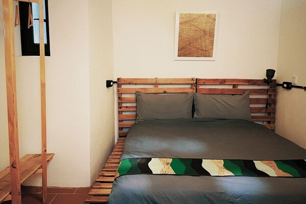 A bed with a wooden headboard, a single pillow, and a blanket with a geometric pattern. - KIVALA Hostel (Jincheng)