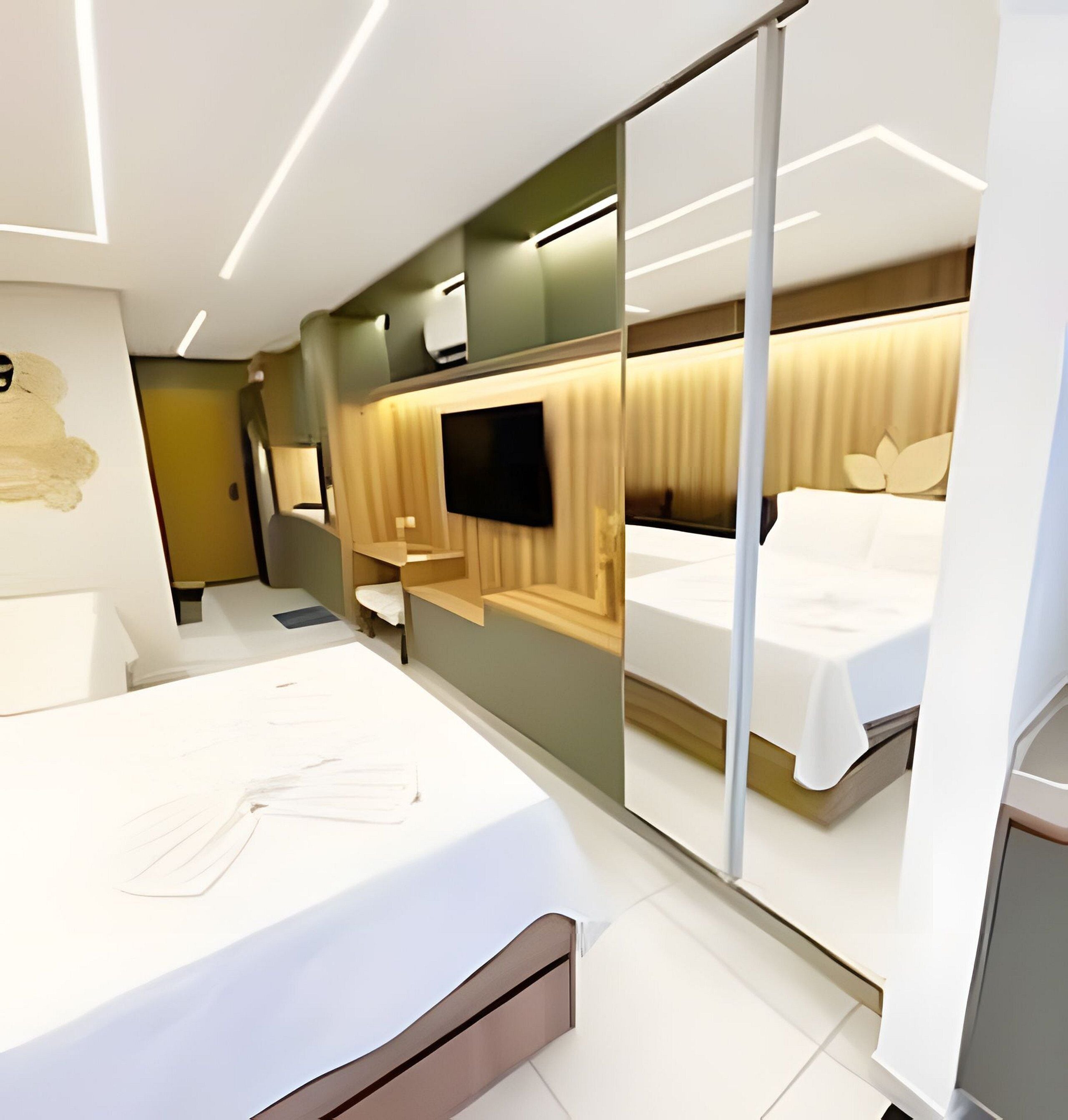 A modern hotel room with a large bed, a flat-screen TV, and a sliding glass door leading to a balcony.