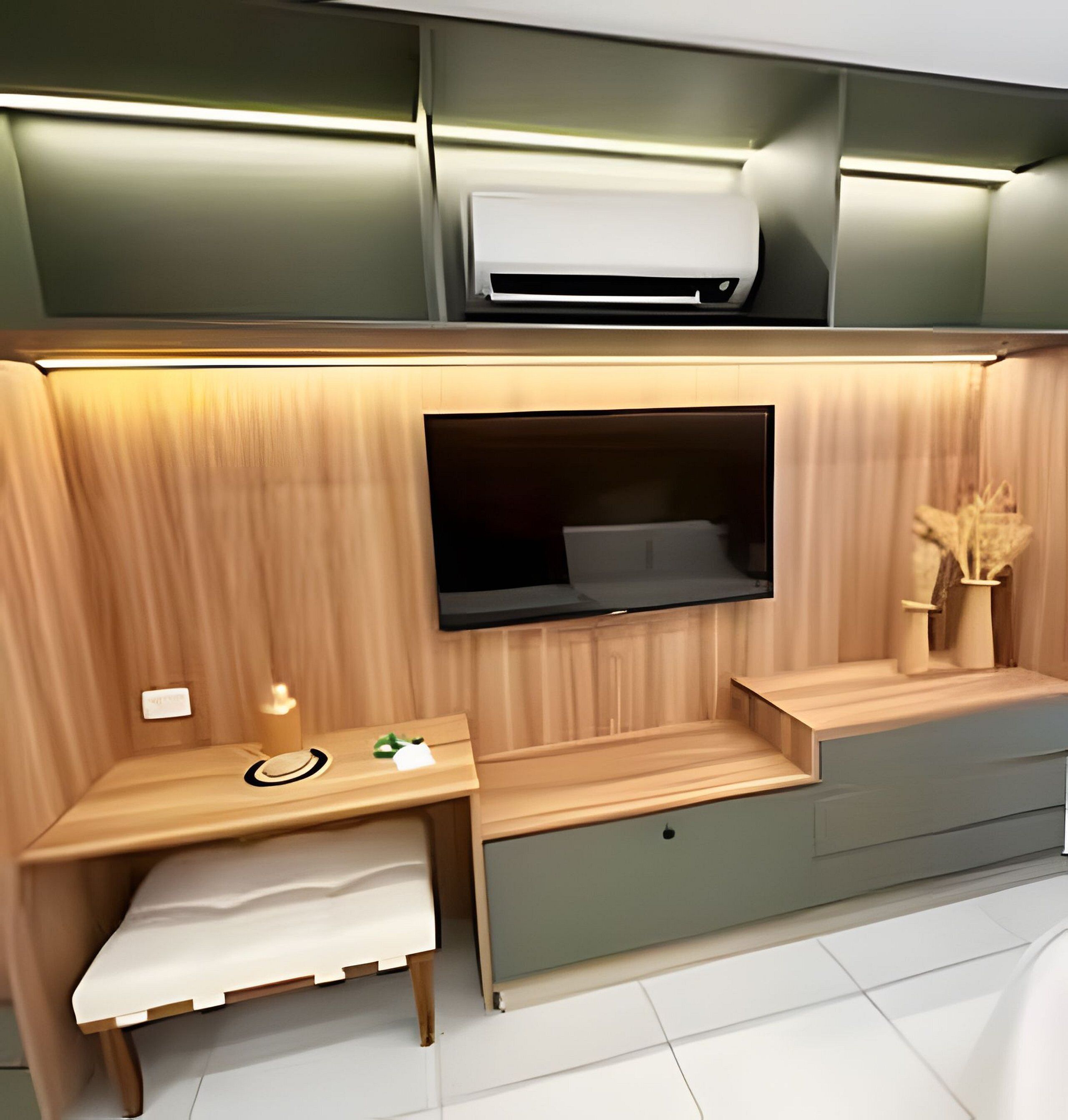 A modern room with a built-in desk, a flat-screen TV, and a small seating area.