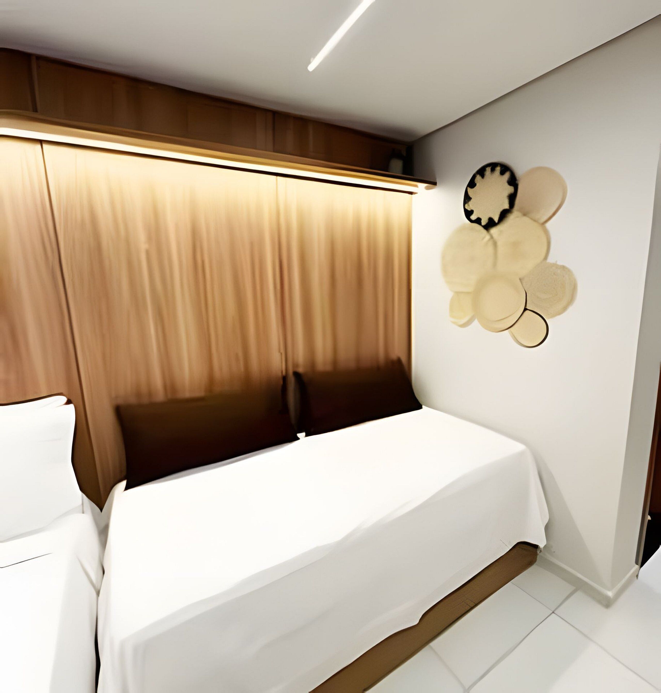 A bedroom with a bed, wooden headboard, and a wall decoration.