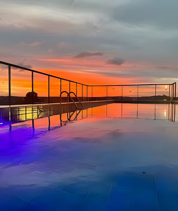 Una piscina al aire libre, sombrillas, sillones reclinables de piscina
