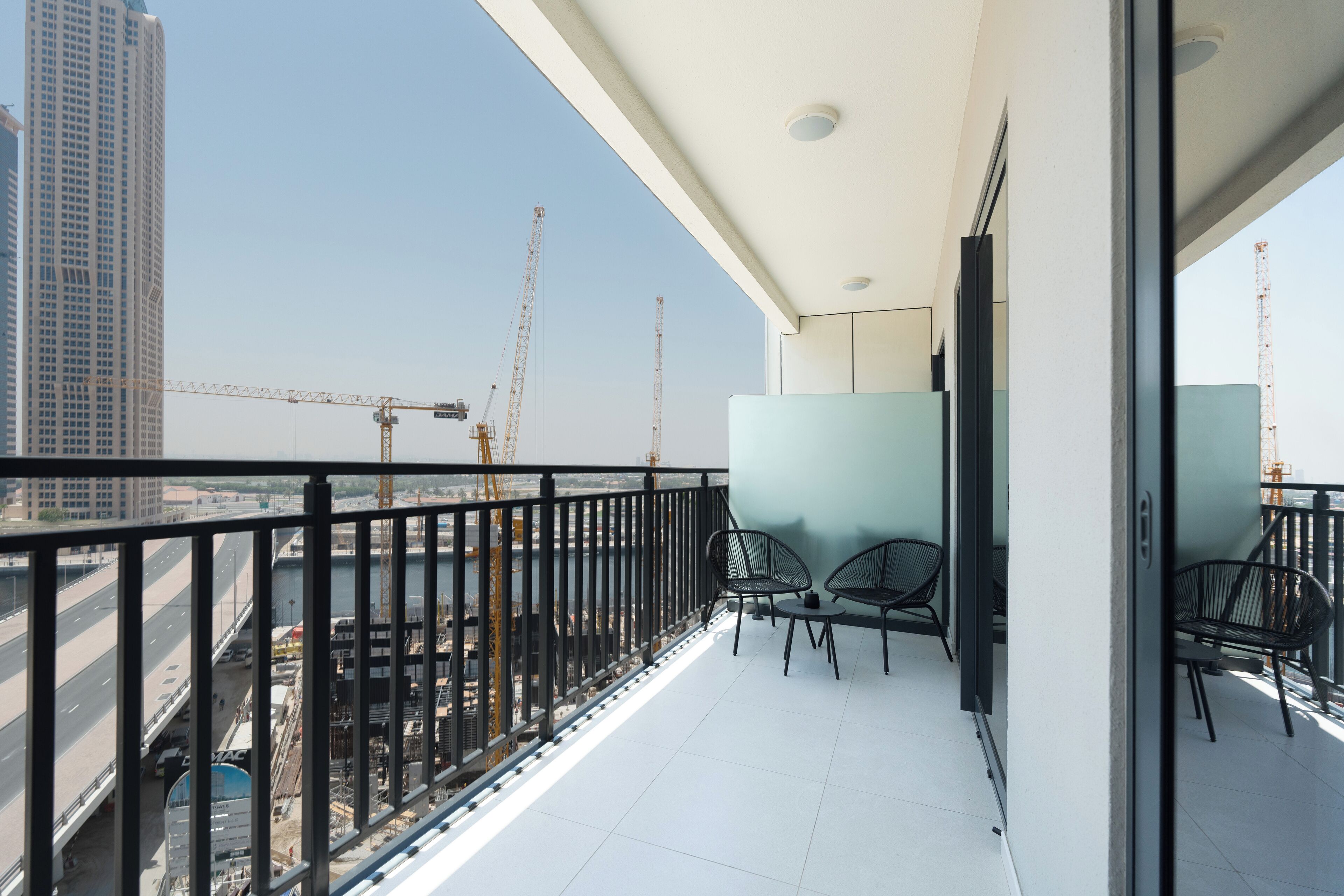 A balcony with a view of a construction site and a high-rise building.