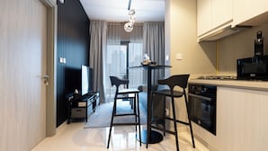 A modern kitchen with a stove, oven, and bar stools. There is a dining area with a table and chairs. - KeyRock Living - Elegant Lake View Apt (Dubai)