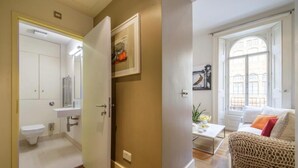 Een kamer met een badkamer, een bank en een raam.