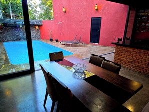Un comedor con una piscina y un edificio rojo al fondo.