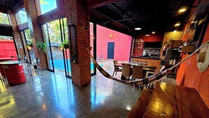 Amplio espacio interior con una hamaca, paredes de ladrillo y vista a la piscina.
