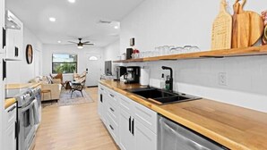 Una cucina moderna con mobili bianchi, un piano di lavoro in legno e un forno integrato.