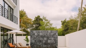 A modern outdoor pool area with a stone wall, lounge chairs, and a sofa.