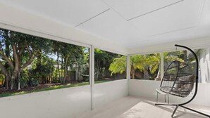 A modern room with large glass doors leading to a garden, a hanging chair, and a minimalist design. - Walking distance to the beach & close to downtown! (Boca Raton)