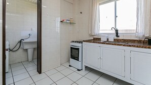 A kitchen with white cabinets, a stove, and a sink. - Beautiful apt 750 m From the Beach of Ingleses Lgr204 (Florianópolis)