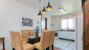 A modern kitchen with white cabinets, a dining area with beige chairs, and pendant lighting. - Beautiful apt 750 m From the Beach of Ingleses Lgr204 (Florianópolis)