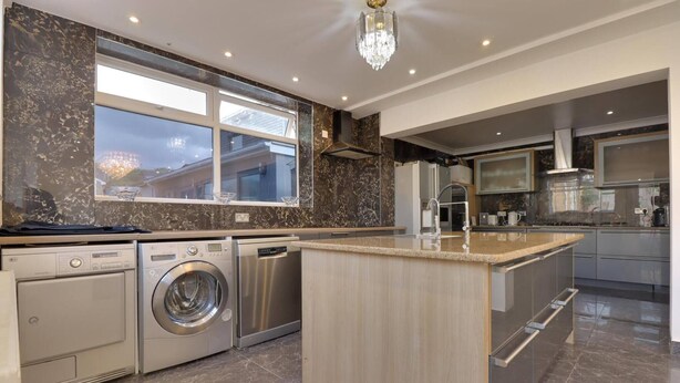 A modern kitchen with a large island, built-in appliances, and a view of the outside. - Luxurious West London Retreat With Hot Tubs & Easy Access to Central London (Greenford)
