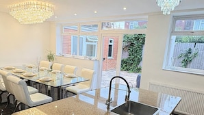 A modern kitchen with a granite countertop, stainless steel sink, and a chandelier. - Luxurious West London Retreat With Hot Tubs & Easy Access to Central London (Greenford)