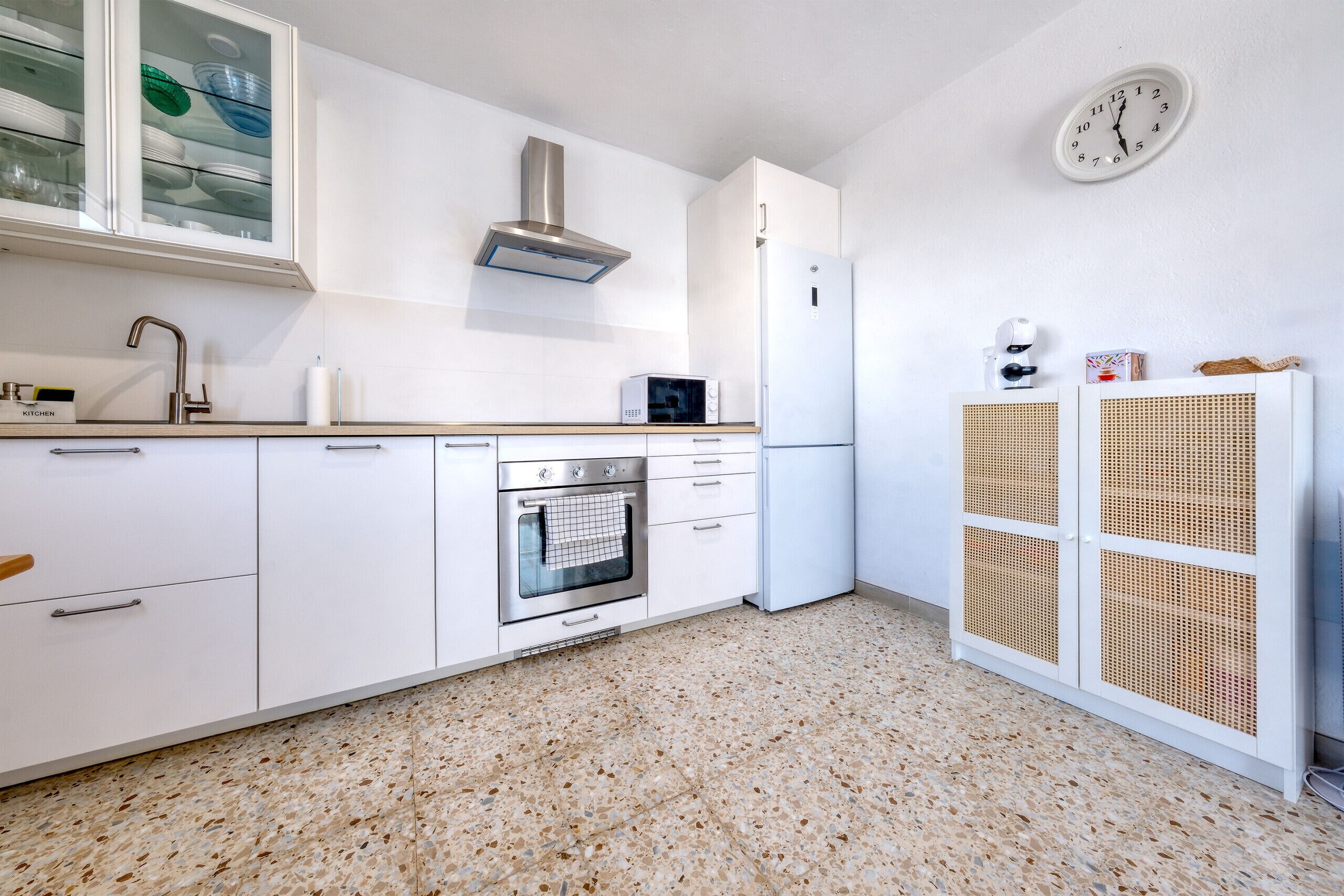 Una cucina moderna con mobili bianchi, un forno in acciaio inossidabile, un forno a microonde e una macchina da caffè.