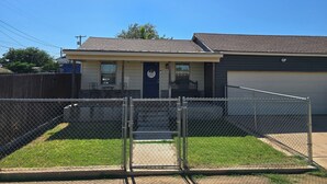 A single-story house with a front porch, a garage, and a fenced yard.