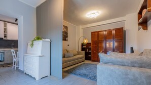 A modern living room with a sofa, a white cabinet with a plant, a wooden wardrobe, and a kitchen area in the background. - Riflessi sul Po by Wonderful Italy (Torino)